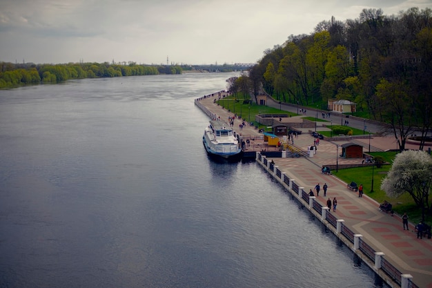 City embankment of the river with a ship and pedestrians Park area of the city