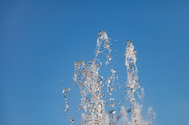 City fountain with splashes and tops jets of water frozen in the air on a clear summer day against the blue clear sky Freshness and benefits of fluid