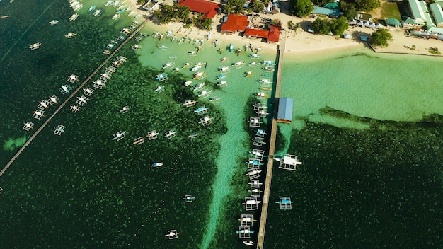 City general luna on the coast of siargao with a pier a port and tourist boats at sunrise aerial vie