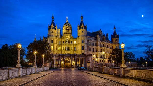 Photo a city is lit up at night with a blue sky