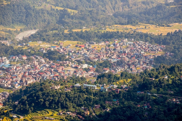 A city is seen from above with a green field and trees.