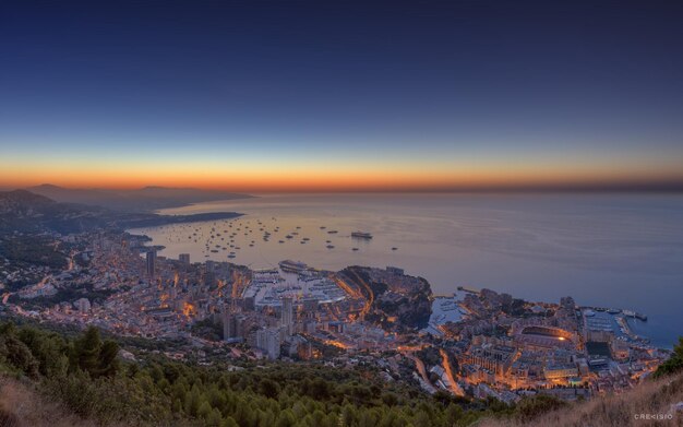 Photo a city is shown with boats on the water and the sky is orange and blue