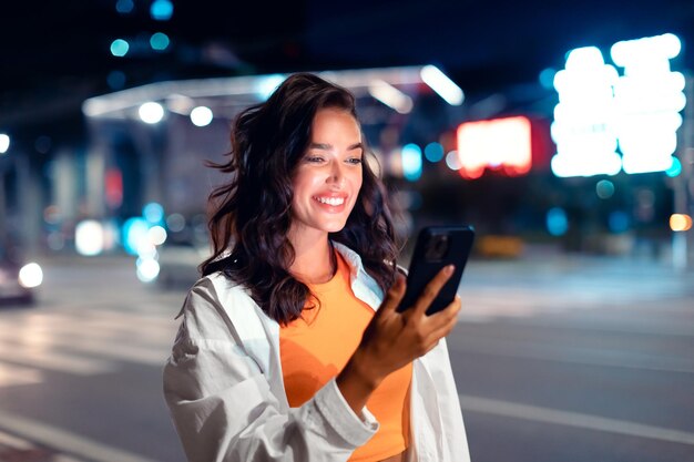 街の灯り 独りで夜を過ごす 幸せな女性 SMSを読む 夕方の街で時間を過ごす 照明がついている