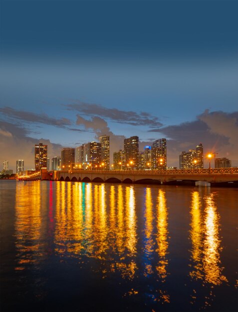 フロリダ州マイアミ市のサンセットパノラマ。ビスケーン湾のスカイラインの夜景にビジネスと住宅の建物と橋があります。