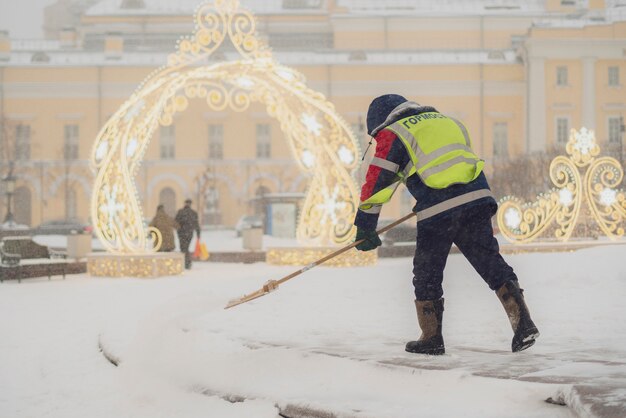 Il ragazzo del servizio urbano pulisce la neve dalle strade con la pala b