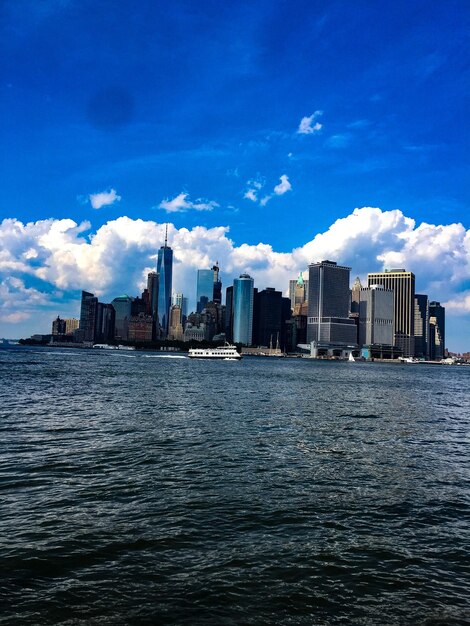 City skyline by river against blue sky