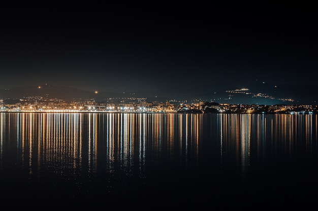 City skyline lights reflecting in the sea during the night