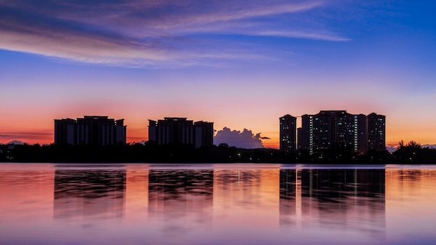 A city skyline with a purple sky and the sun setting behind it