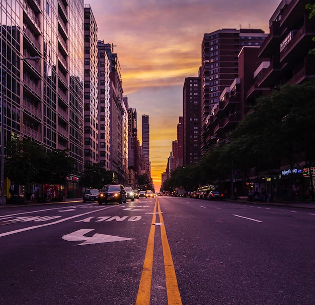 City street amidst buildings against sky during sunset