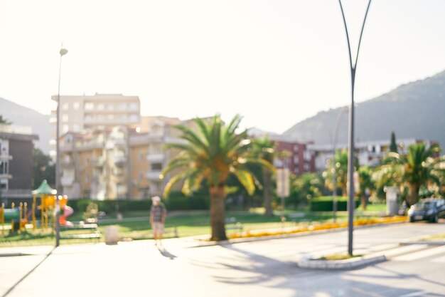 Strada di città con case di palme e montagne sullo sfondo sfocato