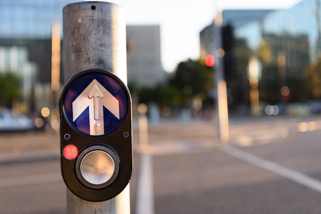 Concetto di traffico urbano: pulsante pedonale per andare a pulsante all'intersezione su sfondo urbano sfocato.