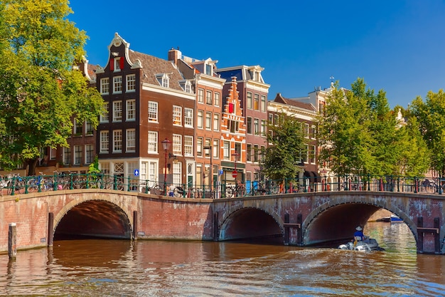 City view of Amsterdam canal, bridge and typical houses, boat and bicycles, Holland, Netherlands.