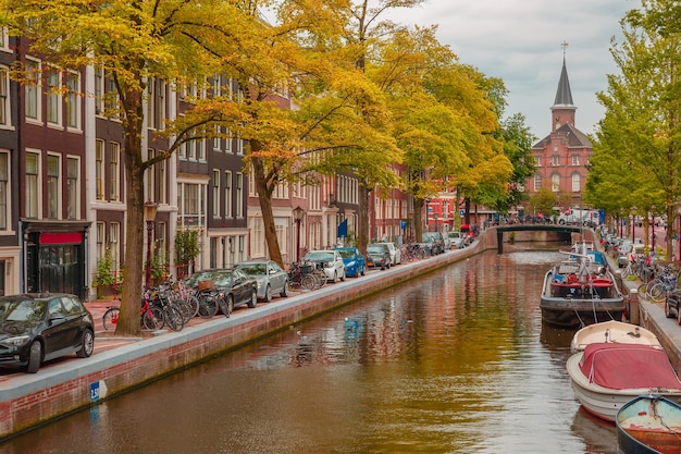 アムステルダムの運河、教会、典型的な家、ボート、自転車、オランダ、オランダの街の景色。