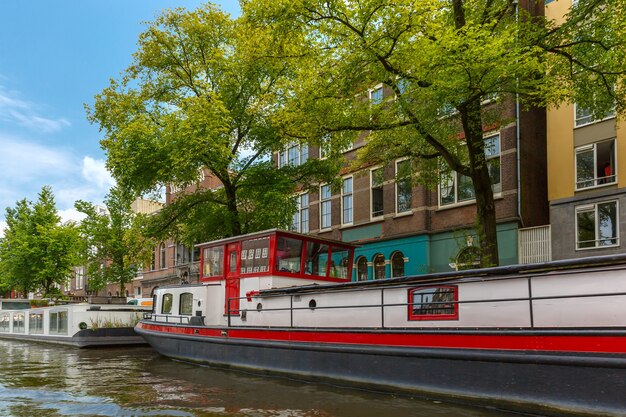 City view of Amsterdam canal and typical houseboat, Holland, Netherlands.