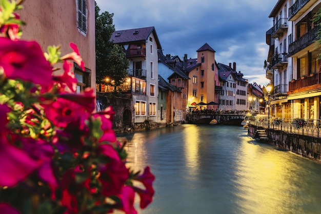 Vista della città di annecy in francia di notte sulle rive del fiume, con fiori in primo piano - messa a fuoco selettiva.