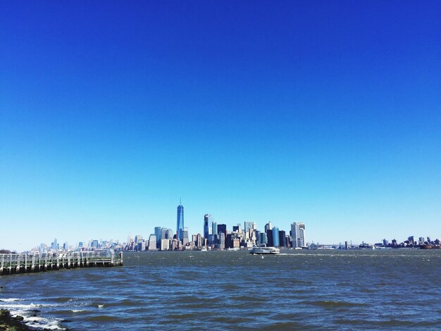 City at waterfront against blue sky