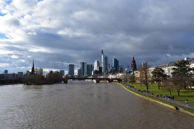 City at waterfront against cloudy sky