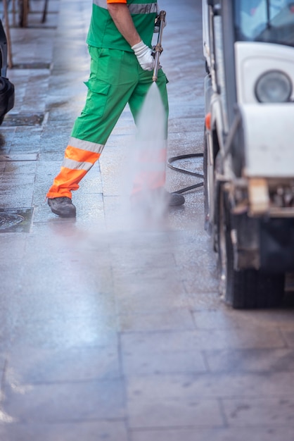 Operaio della città con una pistola a pressione dell'acqua. pulizia strade e arredo urbano, per la prevenzione del covid19, coronavirus