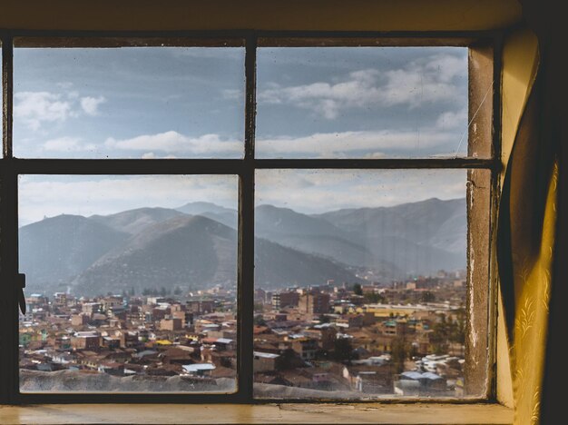 Foto paesaggio cittadino sullo sfondo delle montagne visto dalla finestra