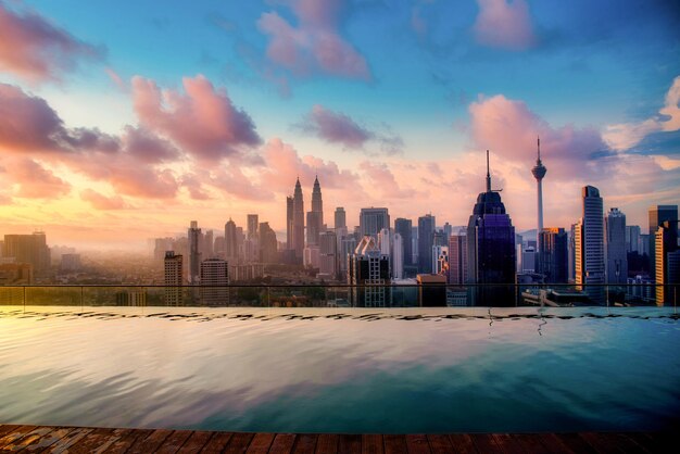 Cityscape of Kuala lumpur city skyline with swimming pool on the roof top of hotel at sunrise in Malaysia.