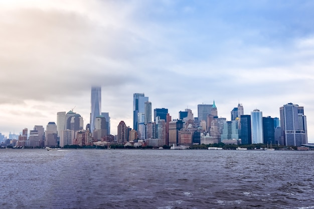 Фото Городской пейзаж финансового района манхэттена с острова свободы, в туманный день.