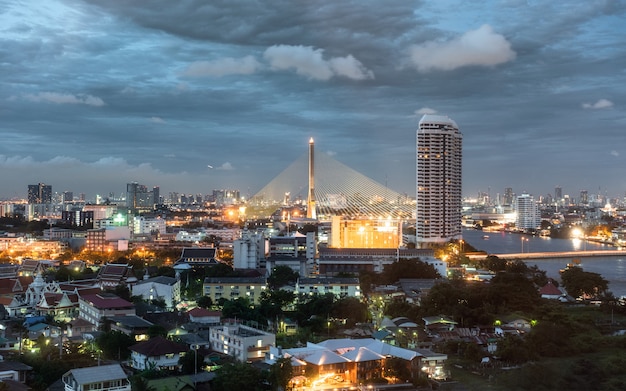 Cityscape of Rama 8 bridge over the Chaophraya river with buildings glowing at dusk