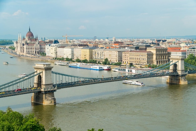 Foto vista sul paesaggio urbano su un ponte delle catene di szechenyi e sulla banca di pest dal punto di vista sulla riva di buda del danubio a budapest ungheria