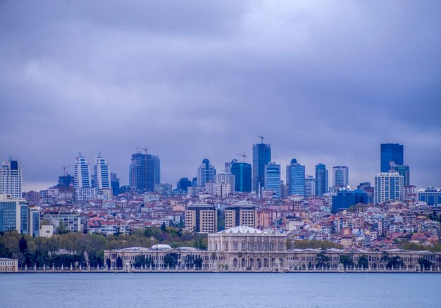 Photo cityscape at waterfront against cloudy sky