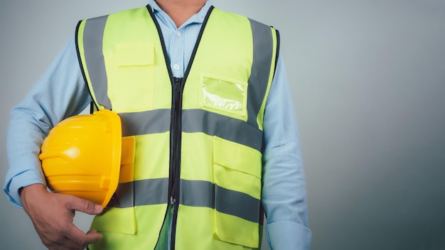 civil engineer architect standing holding a safety helmet on grey background