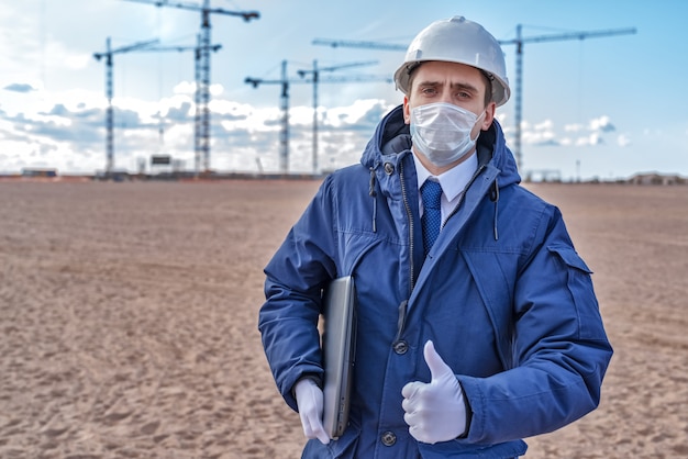 Civil engineer in a white helmet and blue jacket on the site