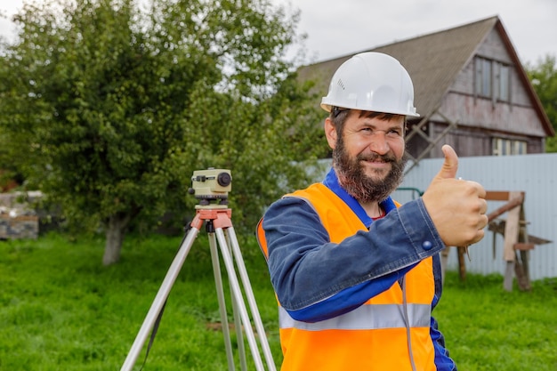 Foto un ingegnere civile con un livello ottico approva il lavoro dei suoi colleghi con un sorriso alzando