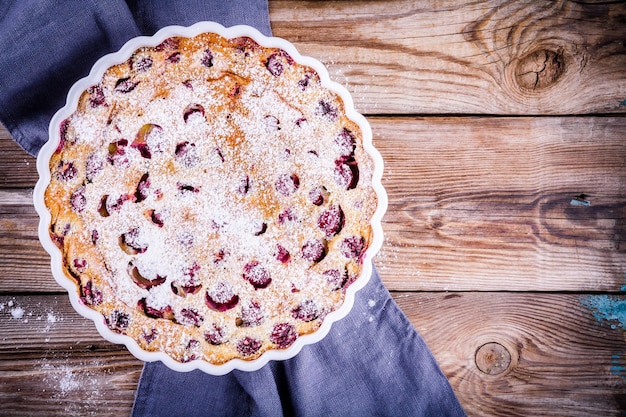 Clafoutis cherry pie on rustic wooden background