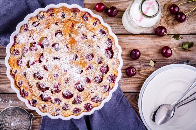 Torta di ciliegie clafoutis su fondo di legno rustico