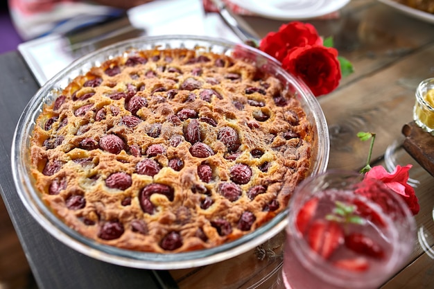 Clafoutis with cherry on a wooden background, traditional French sweet fruit dessert.