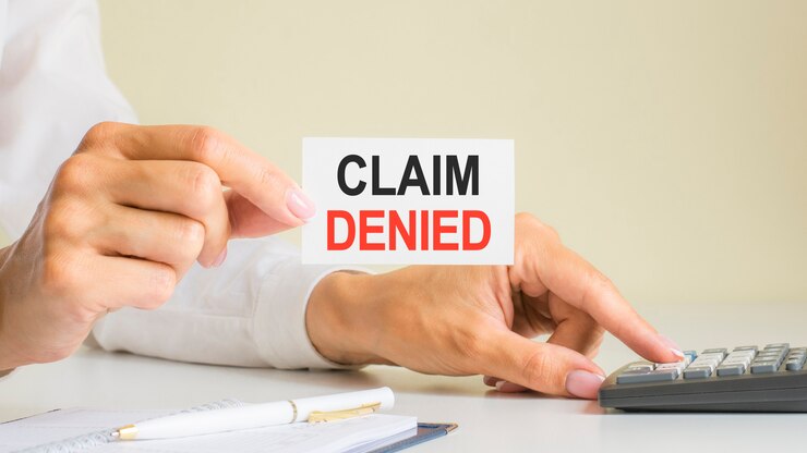 Claim denied, message on business card shown by woman pressing calculator key at workplace in light office, selective focus, business and financial concept