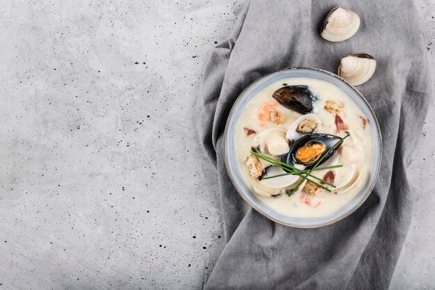 Похлебка из моллюсков в серую тарелку. Основными ингредиентами являются моллюски, бульон, масло, картофель и лук.