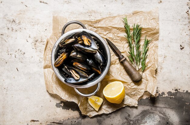 Clams in a pan with lemon and rosemary. On rustic background. Top view