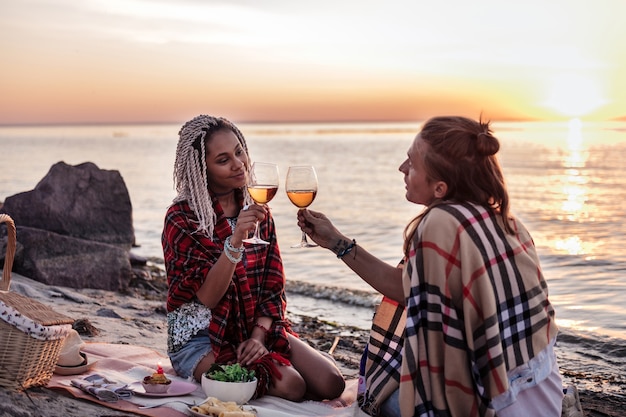 Bicchieri fragorosi. uomo e donna raggianti amorevoli che fanno tintinnare i loro bicchieri con vino che hanno picnic serali