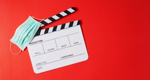 Clapper board and face mask on red background.It is use in video production or movie and cinema industry.