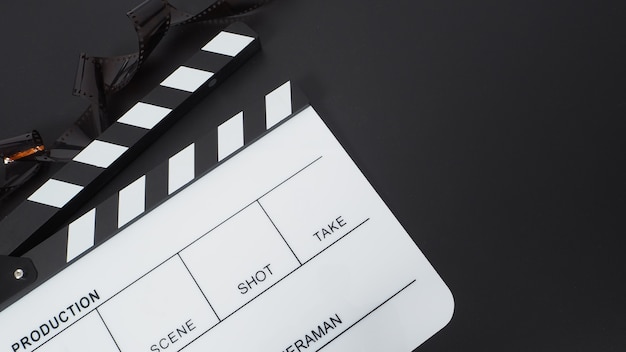 Clapper board or movie slate and film roll. it use in video production and cinema industry on black background.