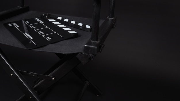 Clapper board or movie slate with director chair use in film\
production in black background