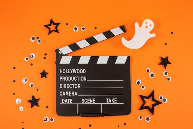 Photo clapper board in spider webs spiders ghost eyes on orange background