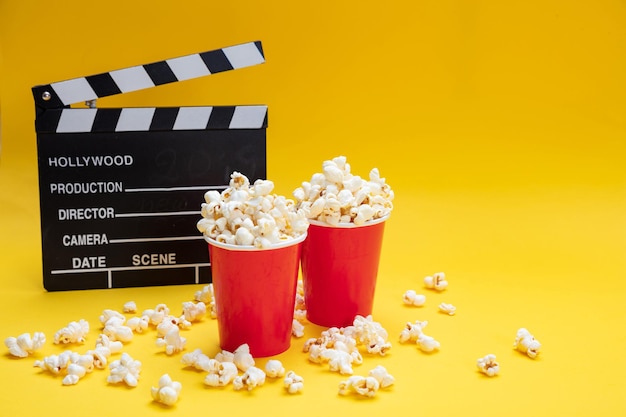Clapperboard and pop corn on yellow color background