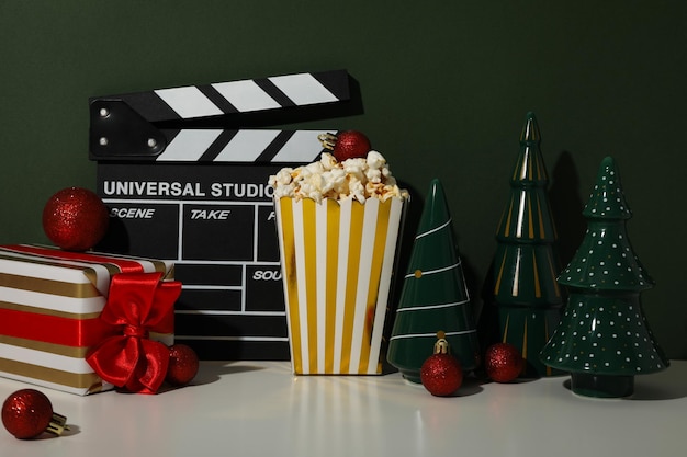 Foto clapperboard popcorn geschenkdoos en kerstversieringen op donkergroene achtergrond