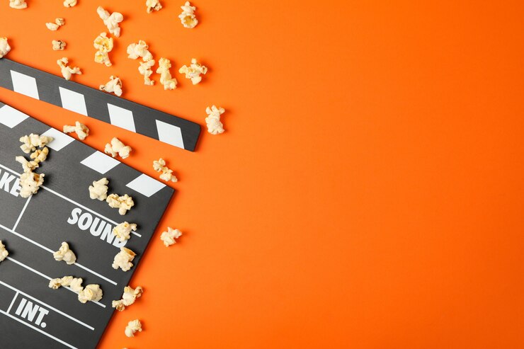 Photo clapperboard and popcorn on orange. food for watching cinema