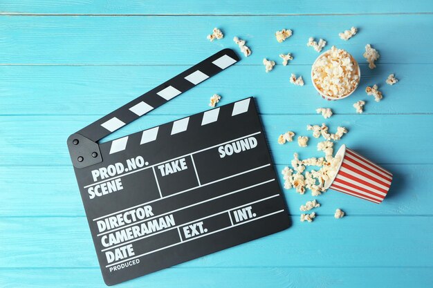 Clapperboard and popcorn on wooden background