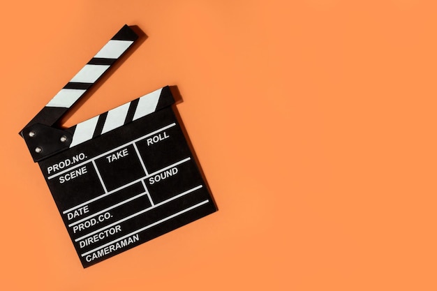 Clapperboard shooting video movies orange background copy space