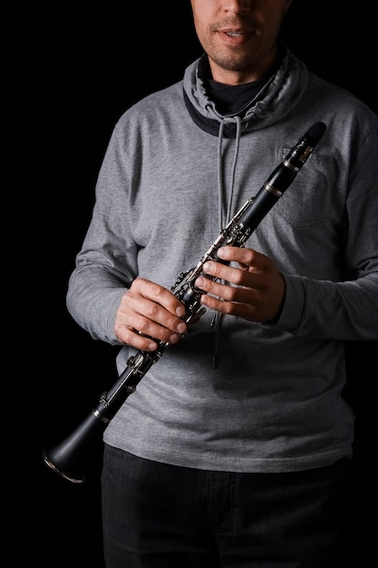 Clarinet in the hands of a man on a black background