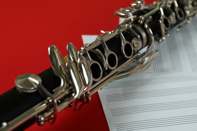 Clarinet and music sheets on red background