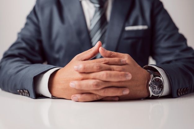 Сложенные руки бизнесмена в строгом костюме, сидящего за рабочим или переговорным столом